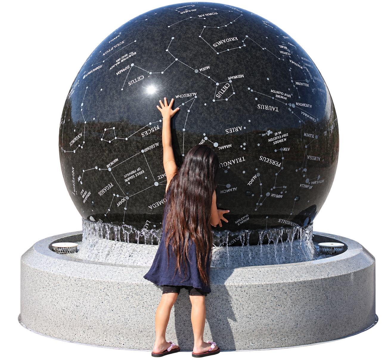 A child touching a large floating granite sphere engraved with constellations